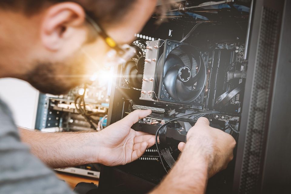 T&eacute;cnico trabajando dentro de una computadora de escritorio abierta